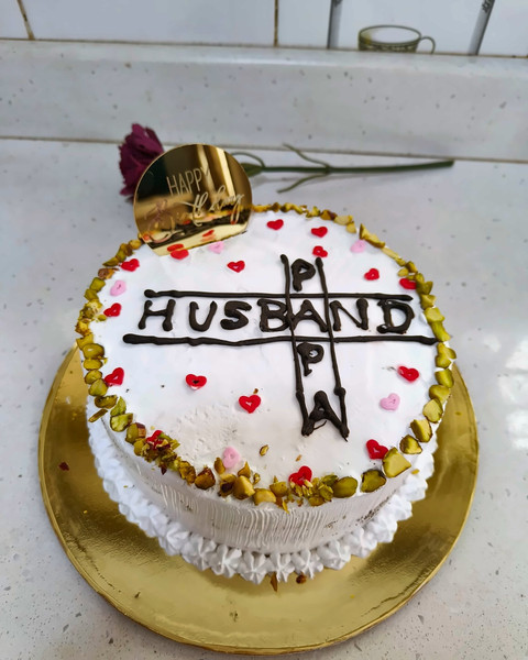 White anniversary-style cake with a Husband topper